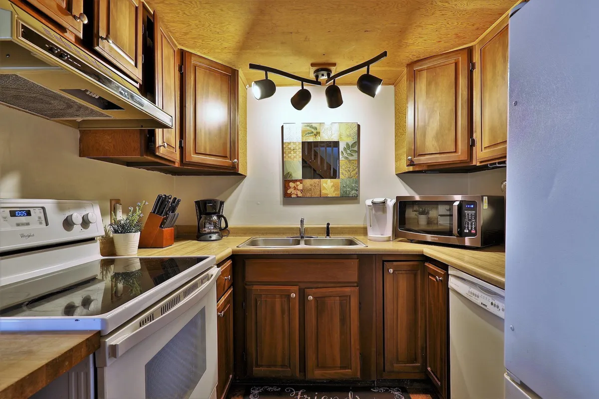 This image features a kitchen with prominent kitchen appliances, wooden cabinets, decorative wall art, and a kitchen sink. The scene is designed for cooking, socializing, and entertaining, encapsulating the atmosphere of a fully equipped, welcoming kitchen.